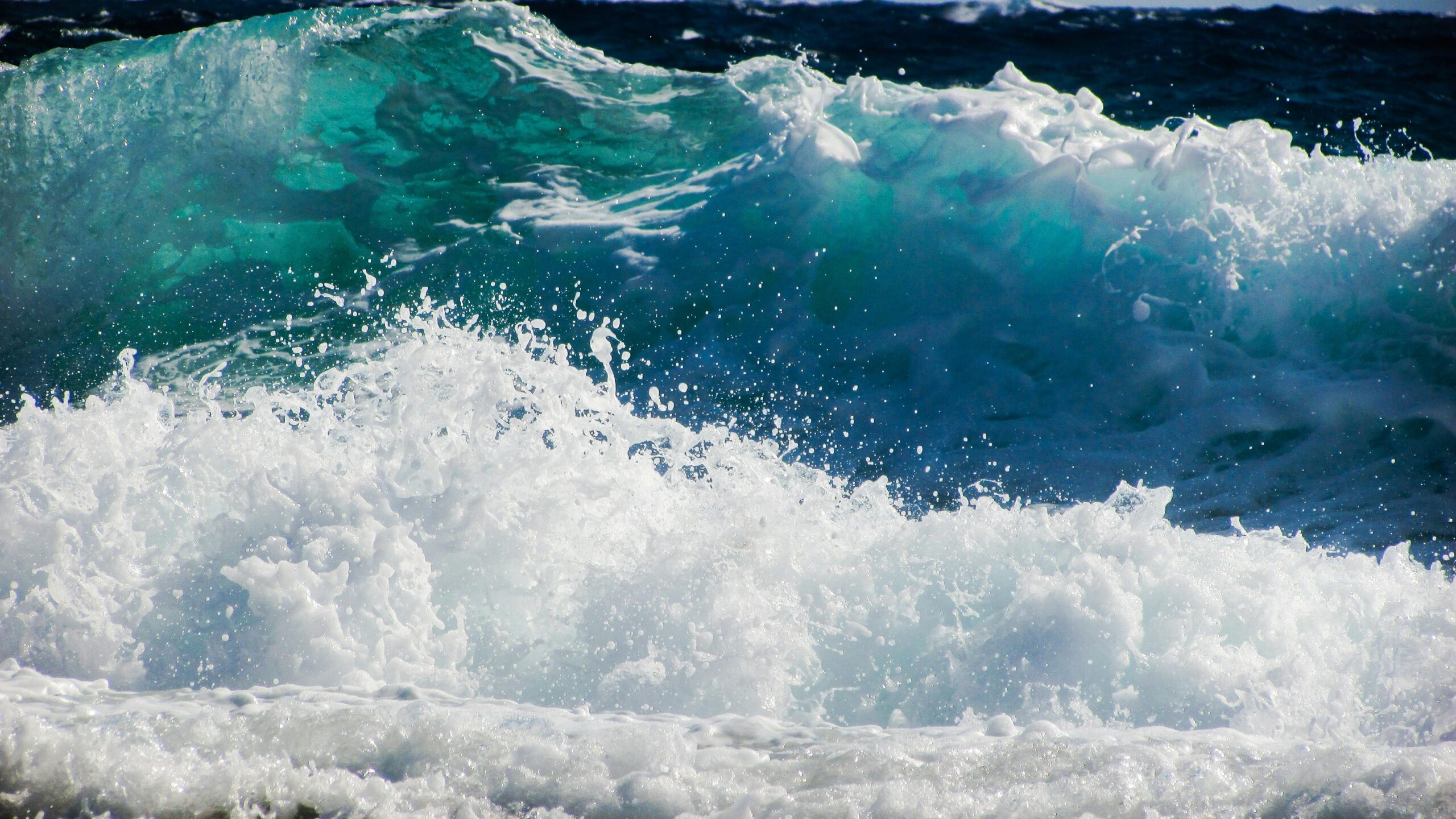 A close-up of dynamic ocean waves with vibrant blue and white sea foam splashing.