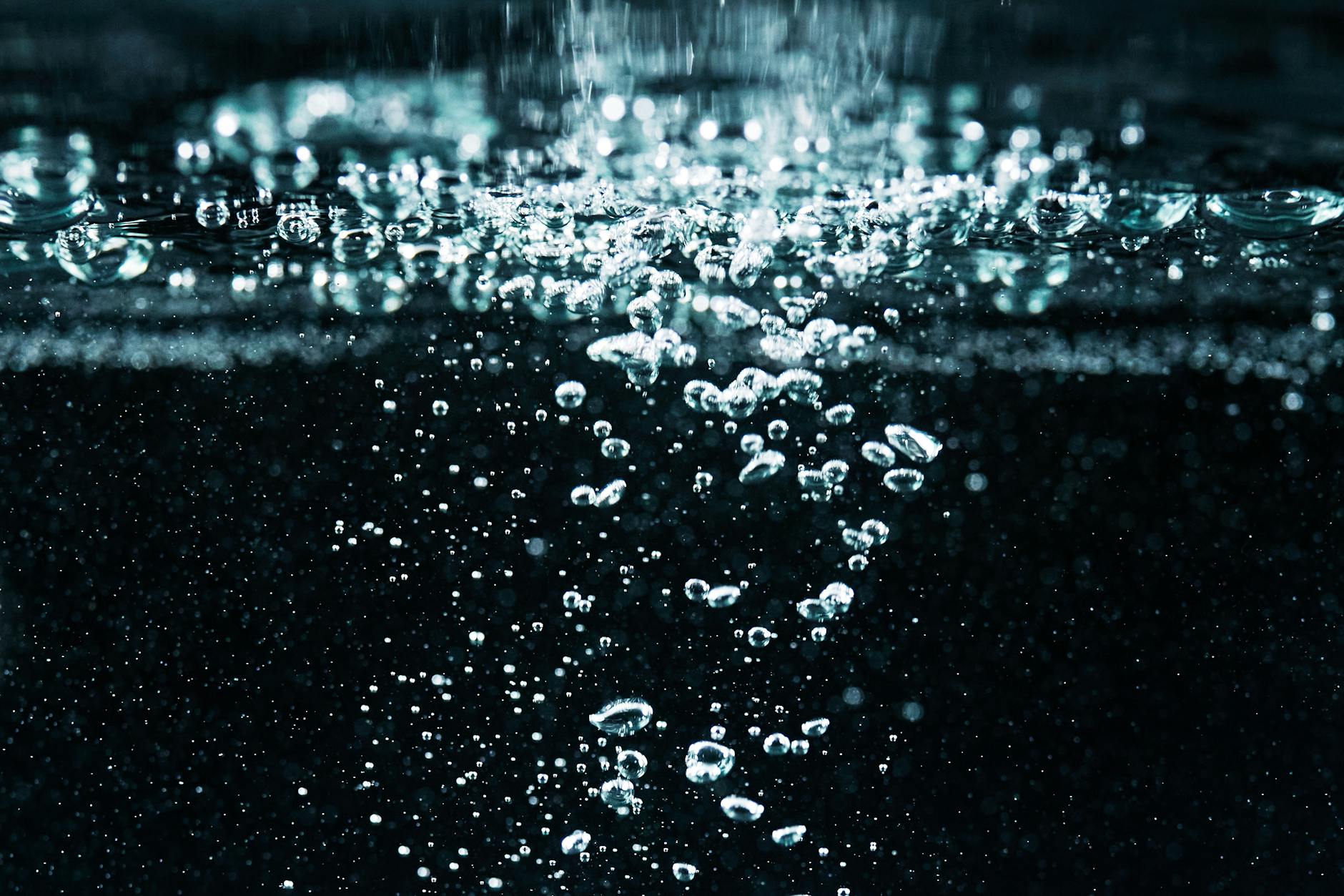 A detailed macro shot of effervescent bubbles rising in water, showcasing fizz and movement.